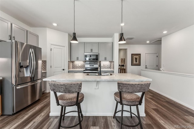 kitchen featuring dark wood-style flooring, a sink, gray cabinets, stainless steel appliances, and backsplash