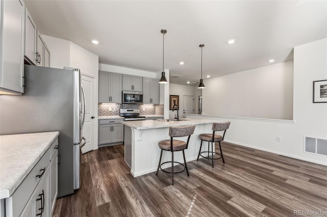 kitchen featuring gray cabinetry, stainless steel appliances, dark wood-style flooring, visible vents, and tasteful backsplash