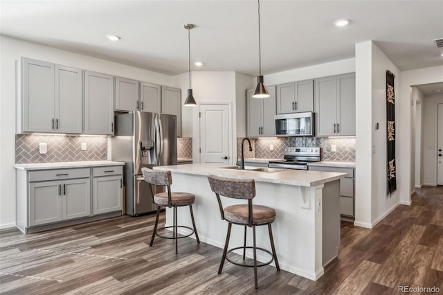 kitchen featuring light countertops, stainless steel appliances, a sink, and gray cabinetry