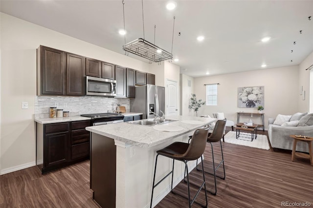 4644 High Springs Ct, Colorado Springs, CO 80917 - kitchen with stainless steel appliances, open floor plan, dark wood finished floors, dark brown cabinetry, and a center island with sink