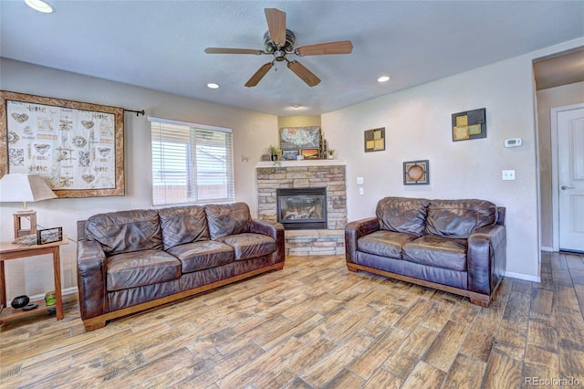 living room with ceiling fan, hardwood / wood-style flooring, and a stone fireplace