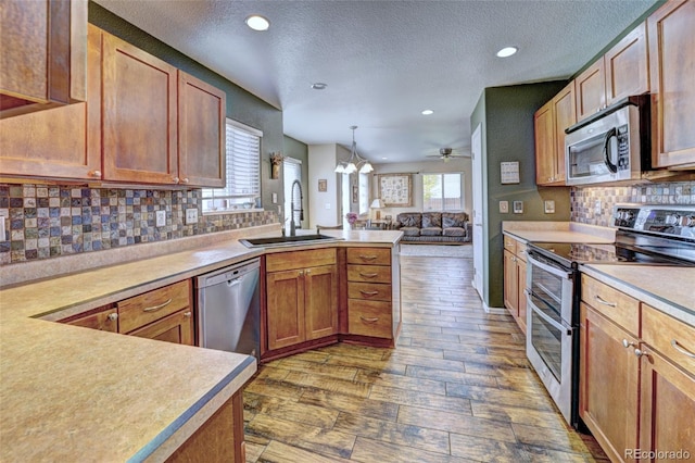 kitchen featuring appliances with stainless steel finishes, sink, backsplash, dark hardwood / wood-style flooring, and decorative light fixtures