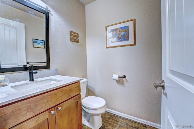 bathroom with toilet, hardwood / wood-style flooring, and vanity