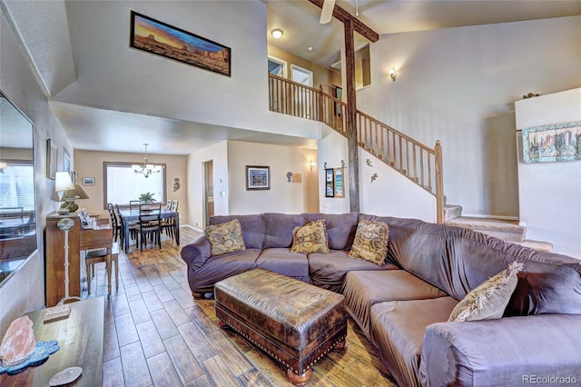 living room with a notable chandelier, wood-type flooring, and high vaulted ceiling