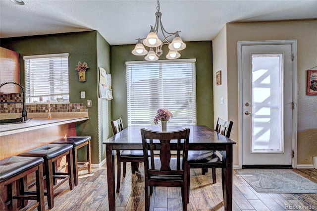 dining space with light hardwood / wood-style floors, an inviting chandelier, a textured ceiling, and a wealth of natural light