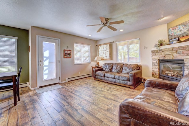 living room featuring baseboard heating, hardwood / wood-style floors, a textured ceiling, and ceiling fan