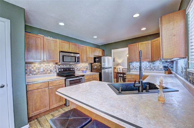 kitchen featuring light hardwood / wood-style flooring, tasteful backsplash, stainless steel appliances, and a breakfast bar