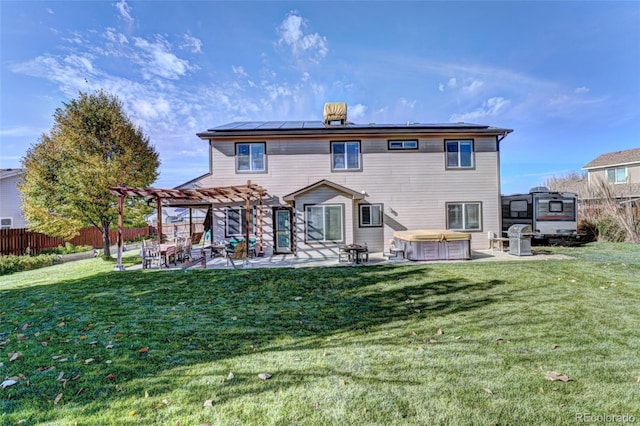 rear view of property featuring a pergola, a hot tub, a patio area, and a yard