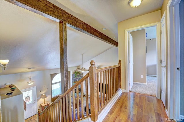 hallway featuring vaulted ceiling with beams, a textured ceiling, and light wood-type flooring