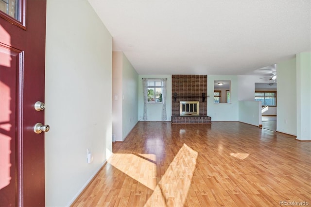 16246 E Hamilton Pl, Aurora, CO 80013 - unfurnished living room featuring light wood-style flooring, a brick fireplace, a ceiling fan, and baseboards