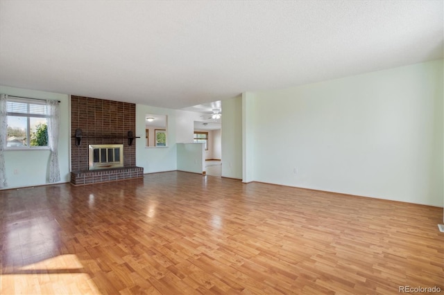 16246 E Hamilton Pl, Aurora, CO 80013 - unfurnished living room with light wood-type flooring, a brick fireplace, and ceiling fan
