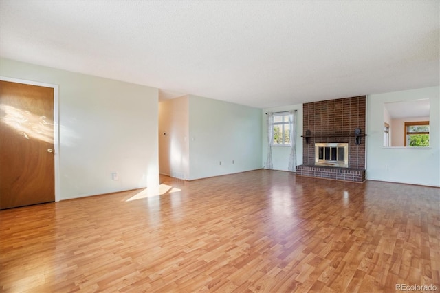 16246 E Hamilton Pl, Aurora, CO 80013 - unfurnished living room featuring light wood-style floors, healthy amount of natural light, and a brick fireplace