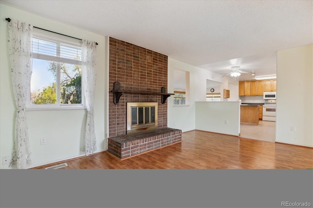 16246 E Hamilton Pl, Aurora, CO 80013 - unfurnished living room featuring light wood-style floors, healthy amount of natural light, a brick fireplace, and a ceiling fan