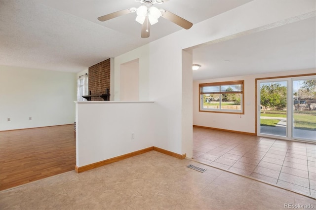 16246 E Hamilton Pl, Aurora, CO 80013 - unfurnished room featuring ceiling fan, baseboards, light tile patterned floors, and a brick fireplace