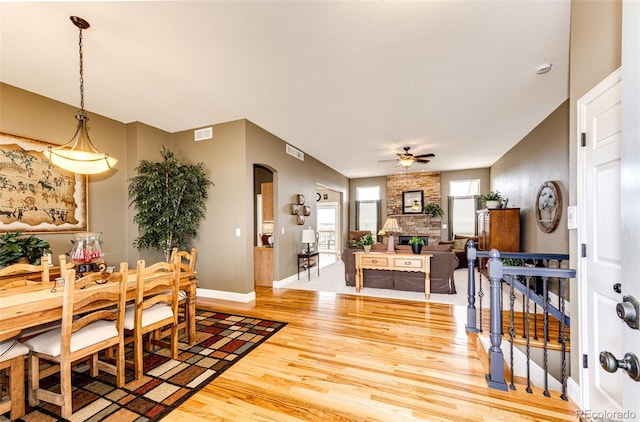 34942 Wagon Wheel Trl, Elizabeth, CO 80107 - dining area featuring arched walkways, light wood finished floors, a ceiling fan, baseboards, and a fireplace