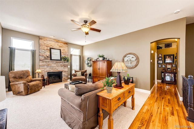 34942 Wagon Wheel Trl, Elizabeth, CO 80107 - living area with arched walkways, ceiling fan, a stone fireplace, baseboards, and light wood-style floors