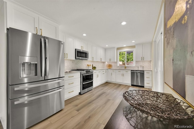 1980 S Kearney Way, Denver, CO 80224 - kitchen featuring appliances with stainless steel finishes, light wood-type flooring, light countertops, white cabinetry, and backsplash
