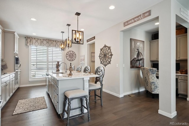 kitchen featuring sink, a breakfast bar area, a center island with sink, and dark hardwood / wood-style flooring