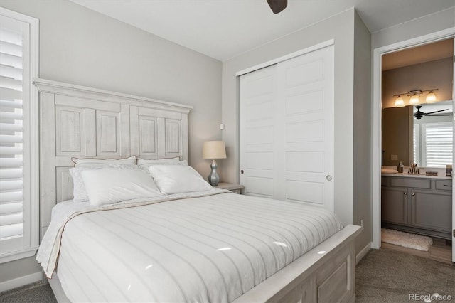 carpeted bedroom featuring a closet, ensuite bathroom, and sink