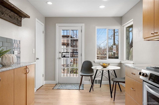 1295 Elm St, Denver, CO 80220 - kitchen with light wood-style flooring, stainless steel stove, light stone countertops, recessed lighting, and light brown cabinets