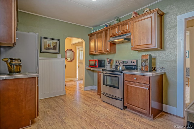 kitchen featuring white fridge, stainless steel range with electric stovetop, and light wood-type flooring