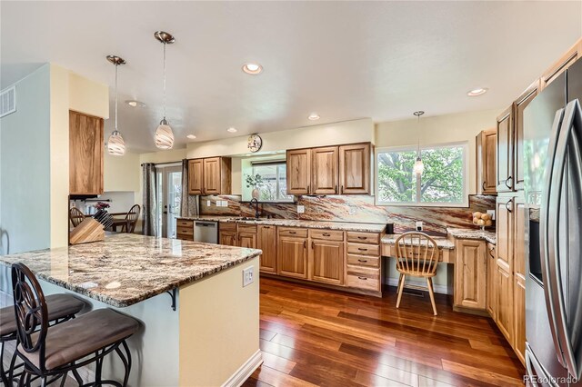 2023 S Rifle St, Aurora, CO 80013 - kitchen featuring appliances with stainless steel finishes, a peninsula, a sink, a kitchen breakfast bar, and dark wood-style flooring