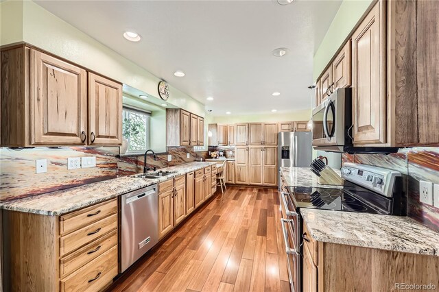 2023 S Rifle St, Aurora, CO 80013 - kitchen with stainless steel appliances, a sink, light stone counters, light wood-type flooring, and recessed lighting