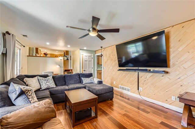 2023 S Rifle St, Aurora, CO 80013 - living area with wood finished floors, wooden walls, ceiling fan, and baseboards