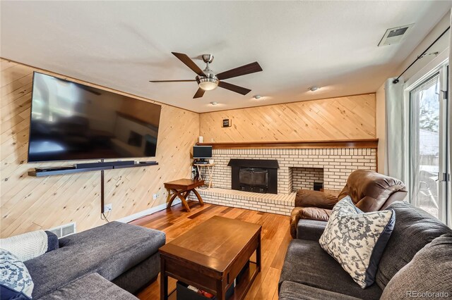 2023 S Rifle St, Aurora, CO 80013 - living room with wood walls, wood finished floors, a ceiling fan, baseboards, and a brick fireplace