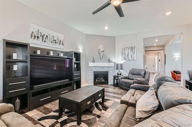 living room featuring a tiled fireplace, ceiling fan, and light hardwood / wood-style floors