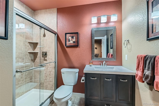 bathroom with a shower with door, tile patterned floors, vanity, and toilet