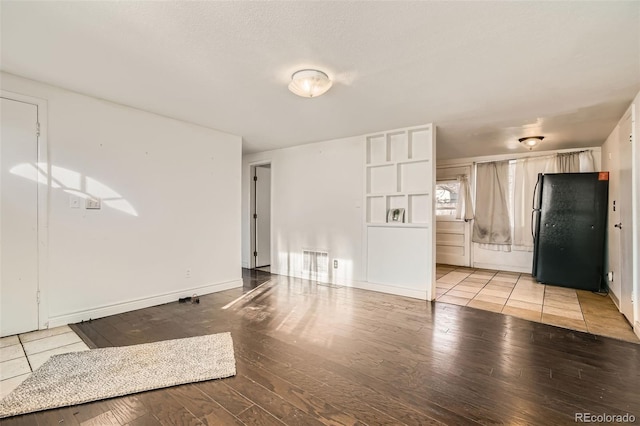 unfurnished living room featuring light wood-style flooring, a textured ceiling, visible vents, and baseboards