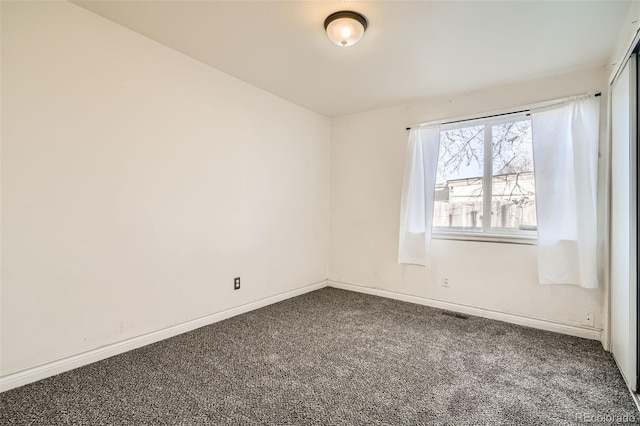 empty room with dark carpet and baseboards