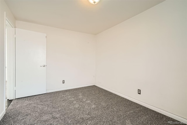 empty room featuring dark colored carpet and baseboards