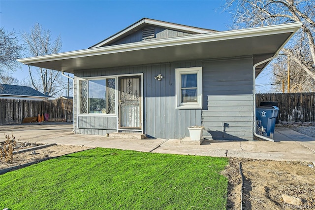 rear view of property with fence, a patio, and a lawn