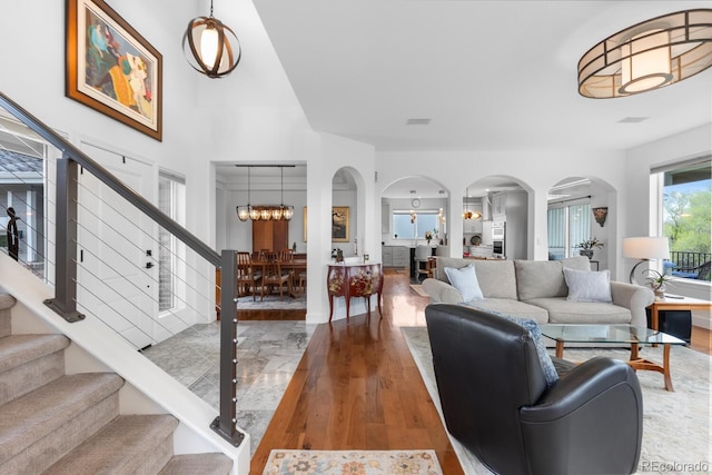 living room featuring arched walkways, wood finished floors, stairs, and a chandelier