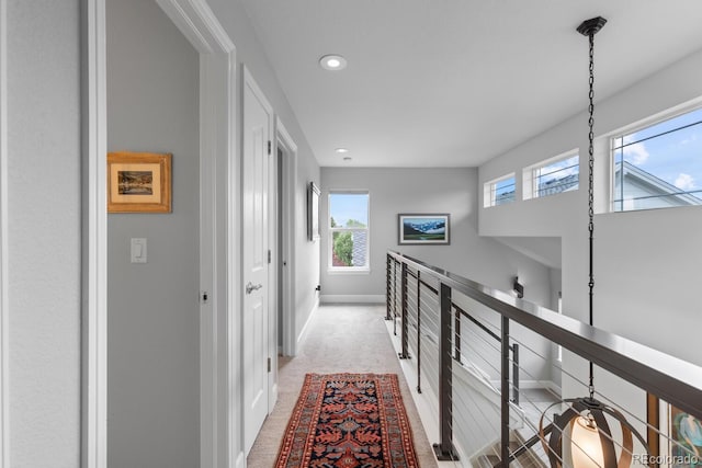 corridor featuring an upstairs landing, recessed lighting, plenty of natural light, baseboards, and light colored carpet