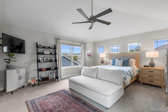 bedroom featuring light colored carpet, multiple windows, ceiling fan, and baseboards