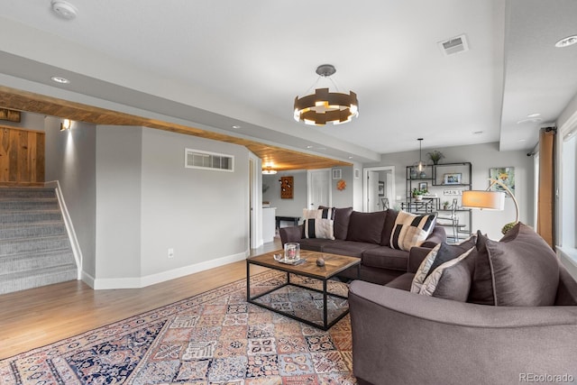 living room featuring a chandelier, wood finished floors, stairway, baseboards, and recessed lighting