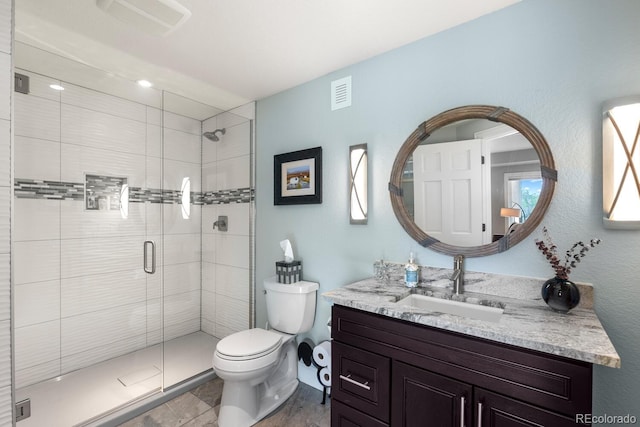 bathroom featuring toilet, a shower stall, and vanity