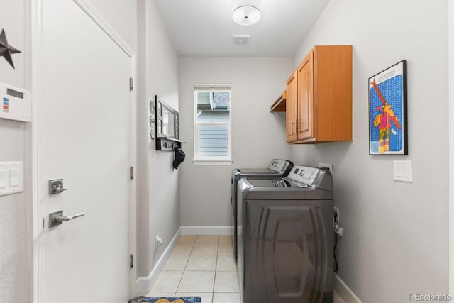 laundry area featuring washing machine and dryer, cabinet space, light tile patterned floors, and baseboards