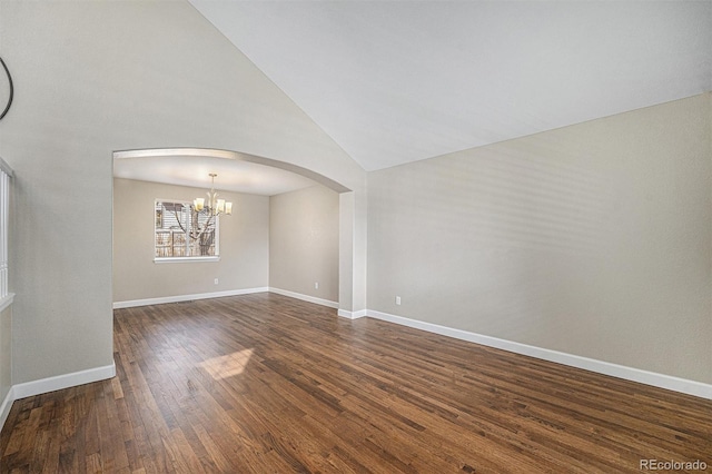 spare room featuring an inviting chandelier, dark wood-style floors, arched walkways, and baseboards