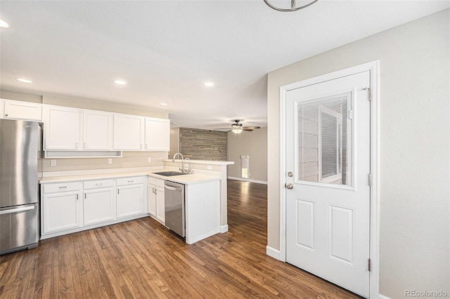 kitchen with a sink, stainless steel appliances, a peninsula, and wood finished floors