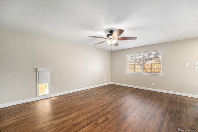 unfurnished room with baseboards, a ceiling fan, and dark wood-style flooring