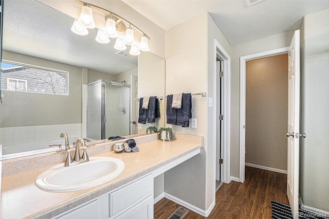 full bathroom featuring a shower stall, vanity, baseboards, and wood finished floors