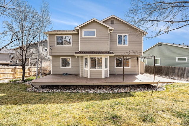 rear view of property featuring a deck, a fenced backyard, and a lawn