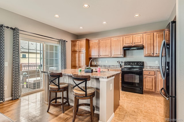 9424 Ridgeline Blvd, Highlands Ranch, CO 80129 - kitchen featuring black appliances, under cabinet range hood, recessed lighting, a kitchen island with sink, and a breakfast bar