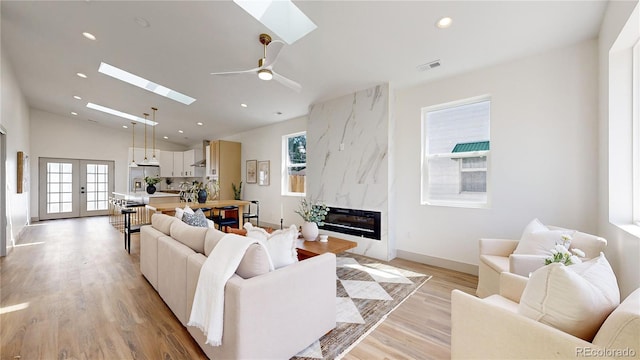 living room with ceiling fan, a skylight, a fireplace, and plenty of natural light