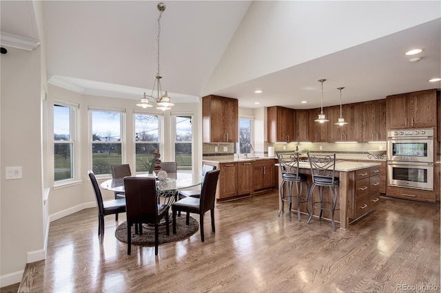 dining room with sink, crown molding, dark wood-type flooring, and high vaulted ceiling