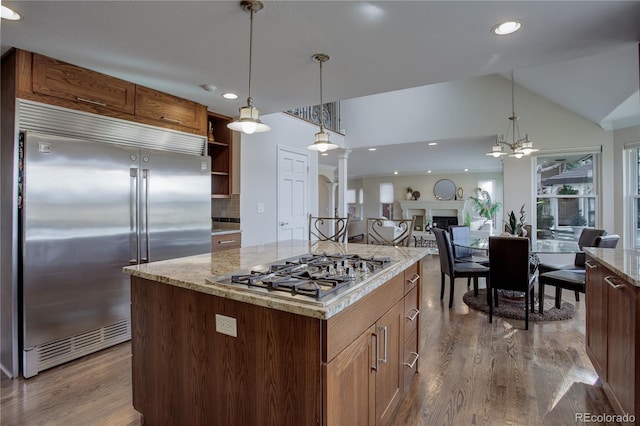 kitchen featuring wood-type flooring, a center island, vaulted ceiling, hanging light fixtures, and stainless steel appliances